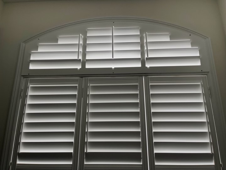 White wood shutters on an arch-top window