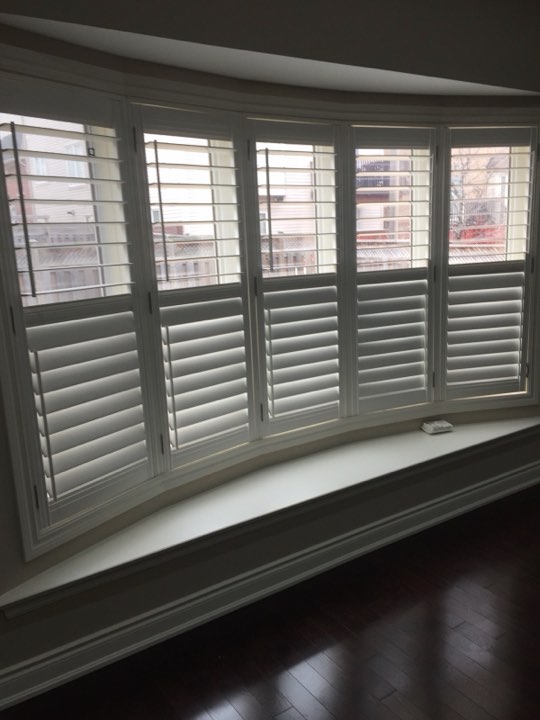 White wood shutters on a curved bay window