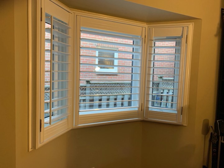 White wood shutters on a bay window in warm light