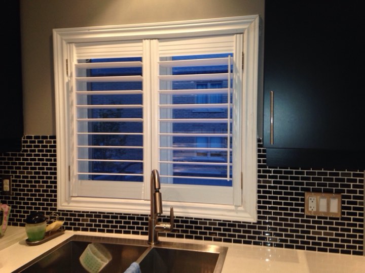 White shutters on a kitchen window over the sink