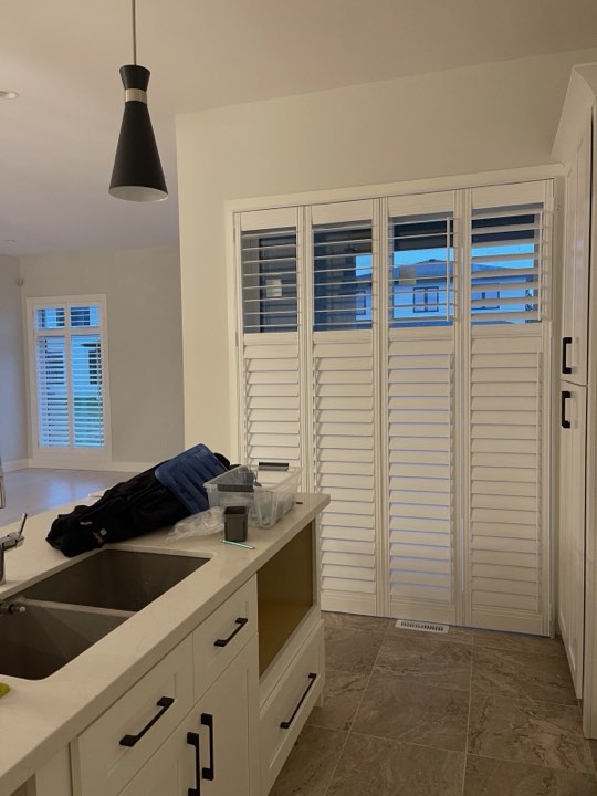 Full-height white shutters in an open-plan kitchen