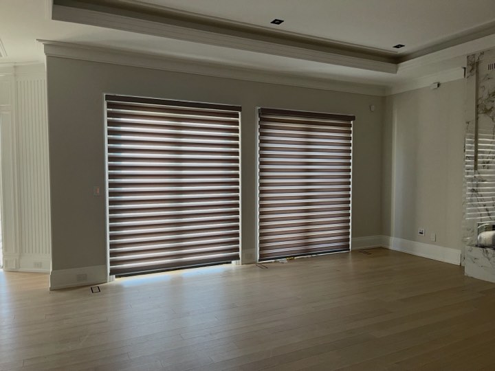 Dark zebra shades on two tall windows in a large room